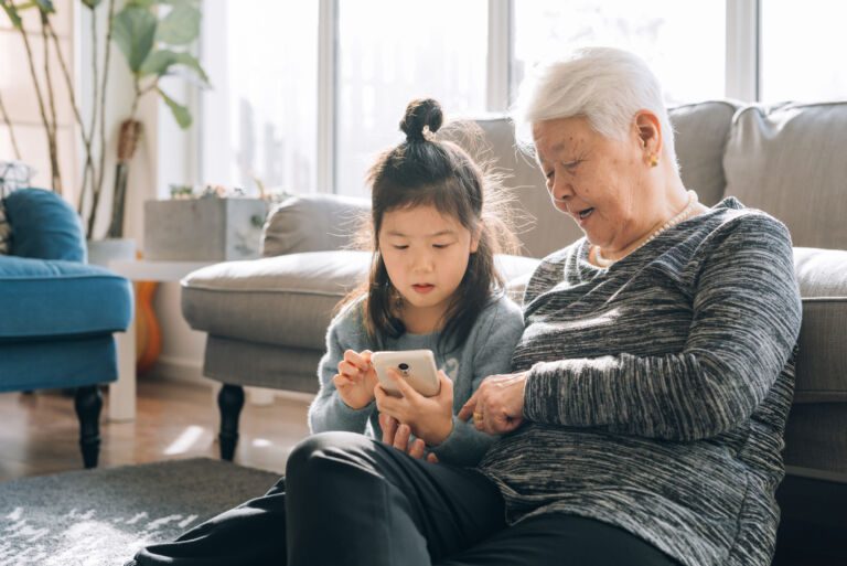 Senior Grandmother Using Smartphone With Her Granddaughter