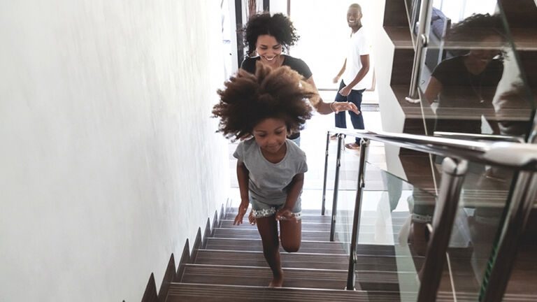 Happy african kid with parents running upstairs into new house